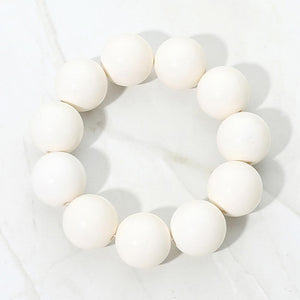 White chunky ball beaded stretch bracelet with oversized round beads, displayed on a white marble background.