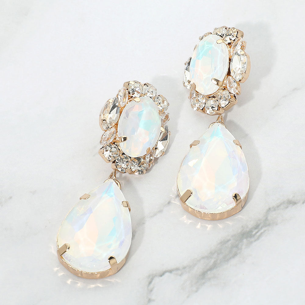 White oval and teardrop dangle earrings on gold on a white marble background