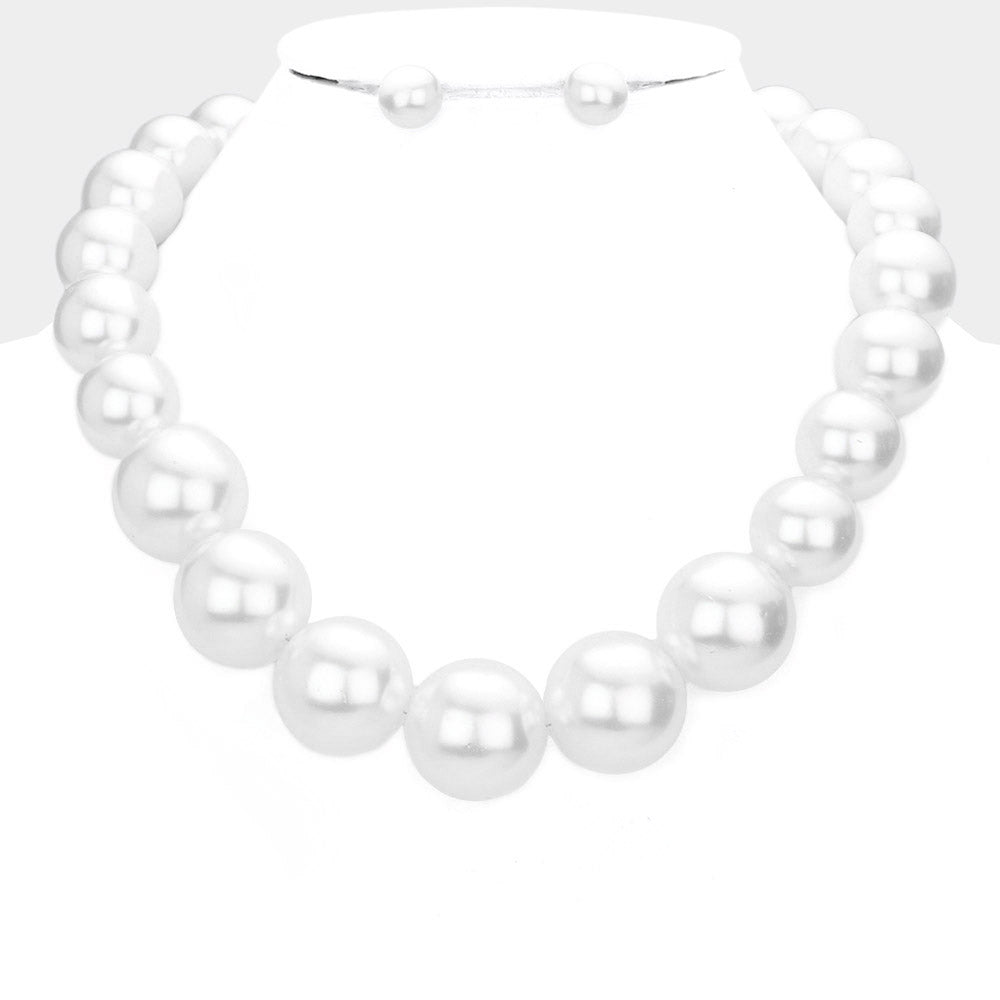 White oversized pearl statement necklace set with large round pearl beads and matching earrings, displayed on a white mannequin bust.