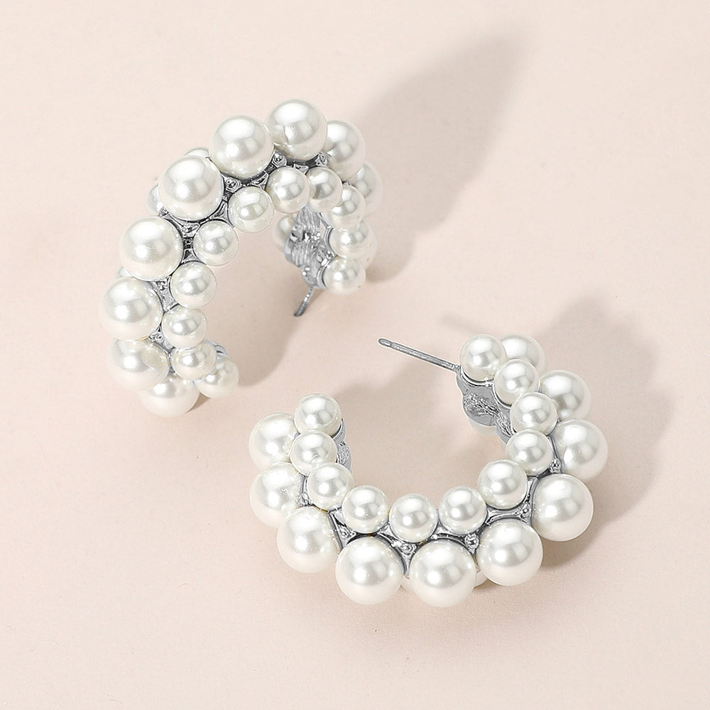 Bridal white pearl hoop earrings on silver with layered pearl cluster design on a pink background