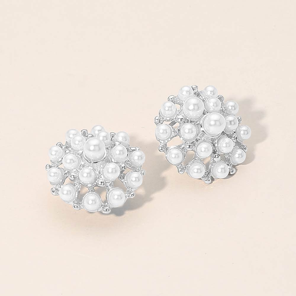 White pearl cluster stud earrings on silver on beige background