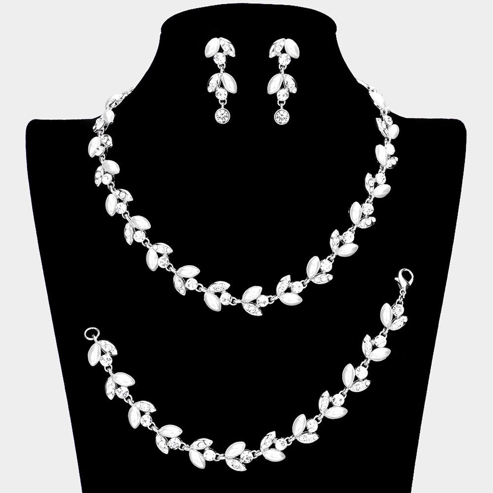 White pearl and crystal bridal jewelry set in a silver finish featuring a coordinating necklace, drop earrings, and bracelet with leaf-inspired accents, displayed on a black jewelry bust with a model wearing the set.