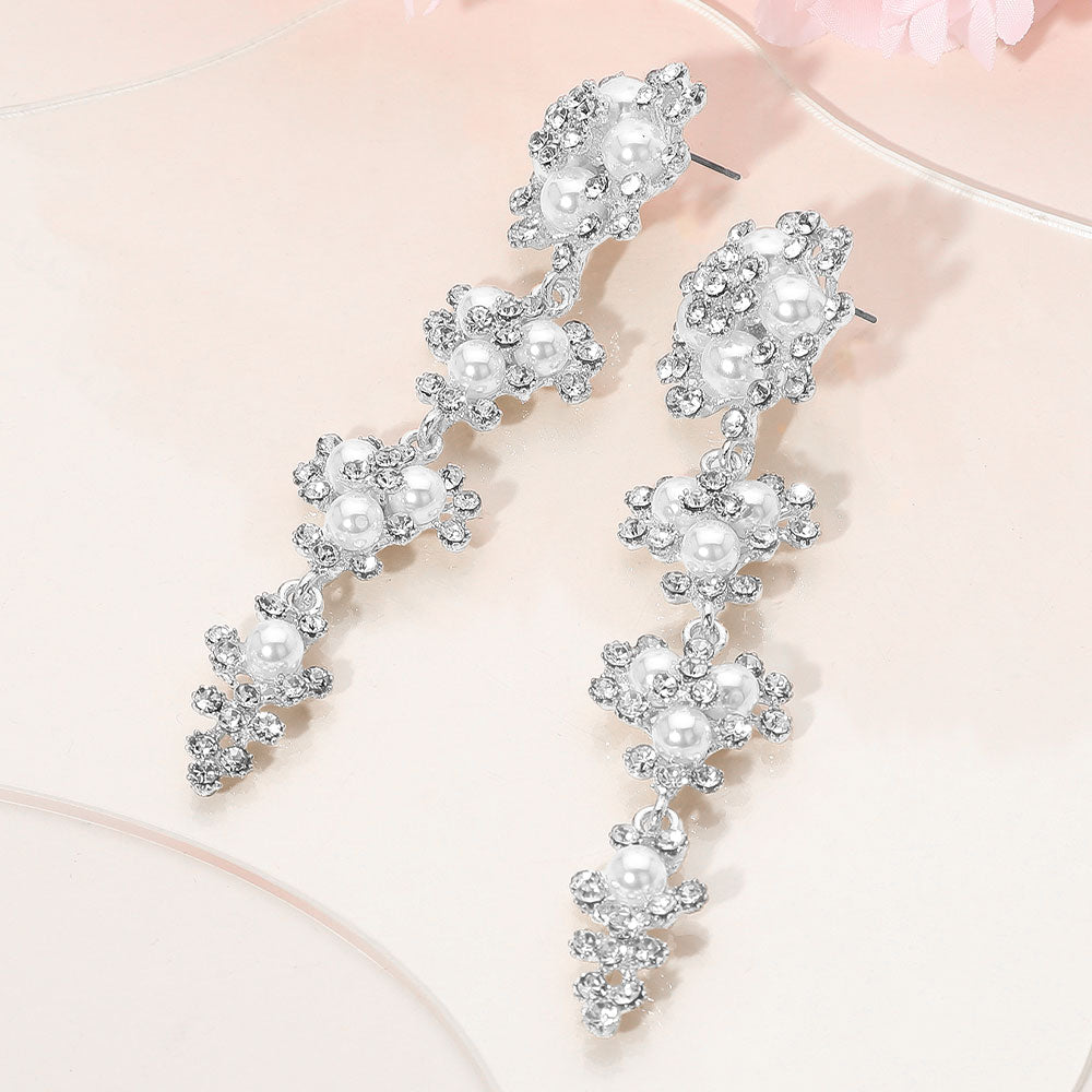 Long white pearl floral rhinestone cluster drop earrings, silver backed, on a soft pink background  — elegant bridal jewelry for weddings, prom, and special events.