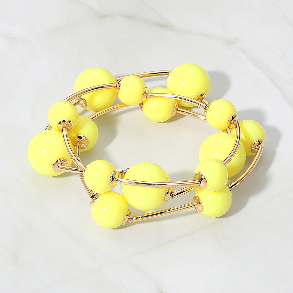 Yellow beaded bracelet with gold accents on a white background