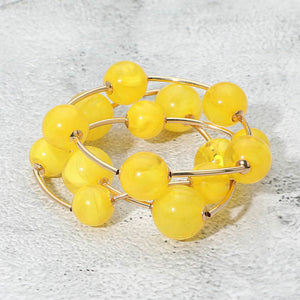 Yellow chunky ball 3-piece stretch bracelet set on gold displayed on a light textured background.