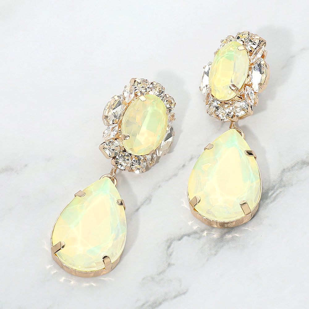 Yellow crystal oval and teardrop dangle earrings on gold on a white marble background