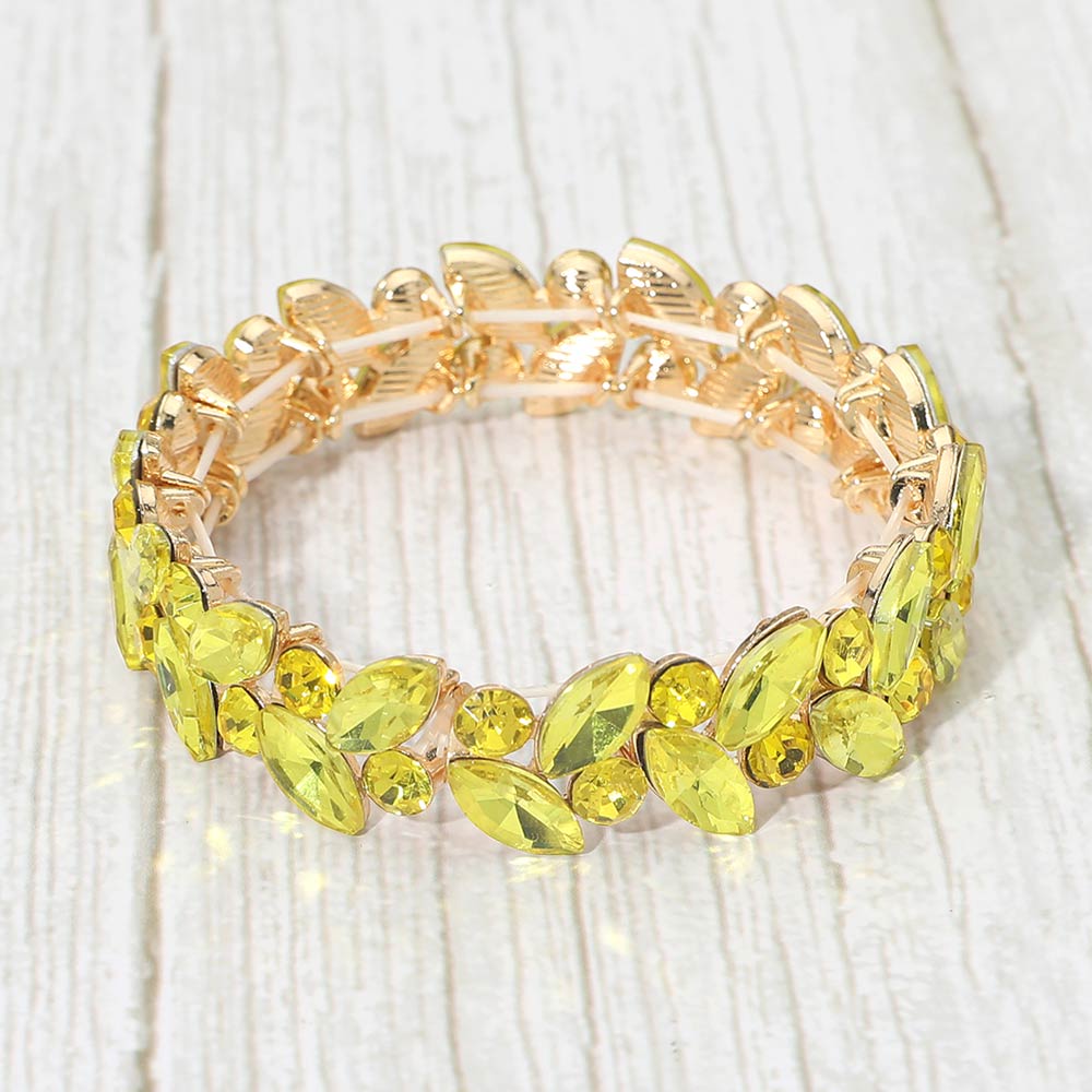 Yellow marquise and round stone cluster stretch bracelet on gold on a light white wood background