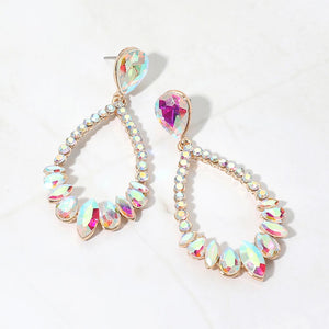 Iridescent AB crystal open teardrop dangle earrings on gold-tone settings, measuring 1.25 inches wide by 2.6 inches long. Stones reflect pink, blue, yellow, and green highlights. Faceted teardrop tops connect to open drops edged with small round crystals and larger teardrop and marquise-shaped stones along the bottom, displayed on white marble.