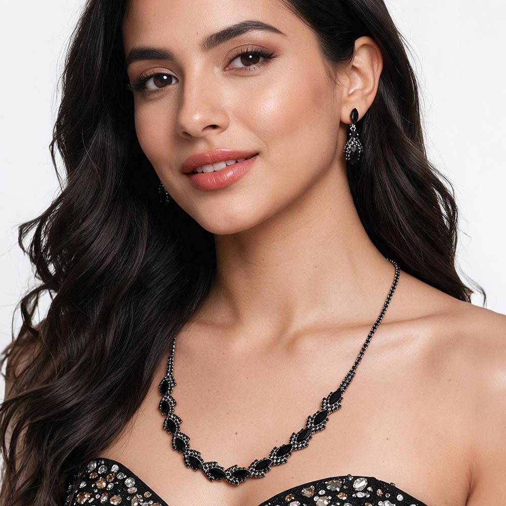 A model wears the black crystal version of this marquise necklace set on silver-tone settings with matching drop earrings and a black strapless dress. Leaf-shaped crystal clusters form a slim decorative line across the neckline. This same-style photo shows how the necklace and earrings sit when worn, against a light gray background.