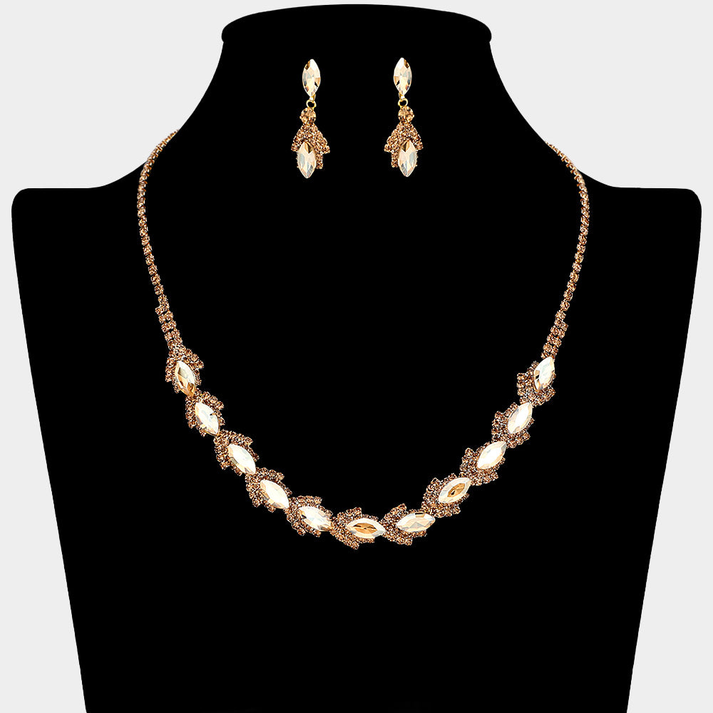 Champagne Gold Stone marquise crystal necklace set on gold-tone settings, with a slim line of small crystals leading to leaf-shaped marquise stones edged in tiny crystals and matching drop earrings. The necklace measures 16 inches plus a 4-inch extender, with 0.4-inch decor; earrings are 0.9 inches long. Displayed on a black necklace bust against a light gray background.