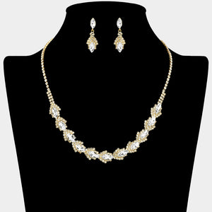 Clear crystal marquise necklace set on gold-tone settings, with a slim line of small crystals leading to leaf-shaped marquise stones edged in tiny crystals and matching drop earrings. The necklace measures 16 inches plus a 4-inch extender, with 0.4-inch decor; earrings are 0.9 inches long. Displayed on a black necklace bust against a light gray background.
