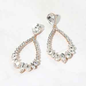 Clear crystal open teardrop dangle earrings on gold-tone settings, measuring 1.25 inches wide by 2.6 inches long. Faceted teardrop tops connect to open drops edged with small round crystals and larger teardrop and marquise-shaped stones along the bottom, displayed on white marble.