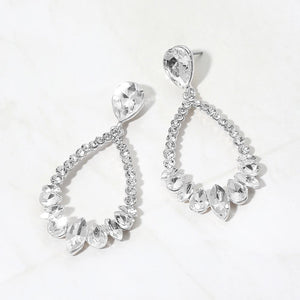 Clear crystal open teardrop dangle earrings on silver-tone settings, measuring 1.25 inches wide by 2.6 inches long. Faceted teardrop tops connect to open drops edged with small round crystals and larger teardrop and marquise-shaped stones along the bottom, displayed on white marble.