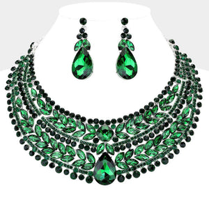 Emerald green crystal statement necklace set on silver-tone metal, featuring a broad, layered bib of marquise and round stones with a large teardrop centerpiece and matching teardrop earrings. Necklace measures 17 inches plus a 2-inch extender, with 2.25-inch decor; earrings are 2.2 inches long. Displayed on a white jewelry bust against a light gray background.