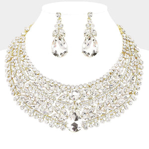 Clear crystal statement necklace set on gold-tone metal, featuring a broad, layered bib of marquise and round stones with a large teardrop centerpiece and matching teardrop earrings. Necklace measures 17 inches plus a 2-inch extender, with 2.25-inch decor; earrings are 2.2 inches long. Displayed on a white jewelry bust against a light gray background.