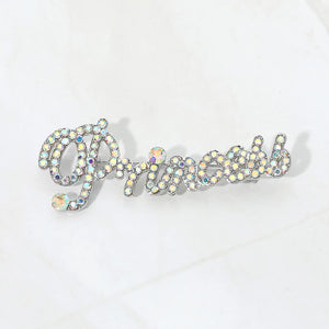 Silver-tone “Princess” brooch with iridescent AB crystals covering flowing, connected script lettering and a large looping capital P, measuring approximately 2.8 inches wide by 1.1 inches tall, displayed on a white background.