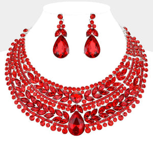 Red crystal statement necklace set on silver-tone metal, featuring a broad, layered bib of marquise and round stones with a large teardrop centerpiece and matching teardrop earrings. Necklace measures 17 inches plus a 2-inch extender, with 2.25-inch decor; earrings are 2.2 inches long. Shown here on a white mannequin bust. 