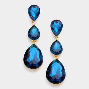 A pair of teal blue zircon crystal teardrop earrings with gold links on a white background