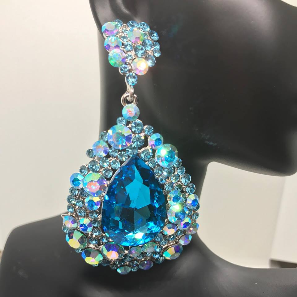 A large, chunky, aqua-colored earring with AB stones and silver backed, displayed on a black mannequin ear.